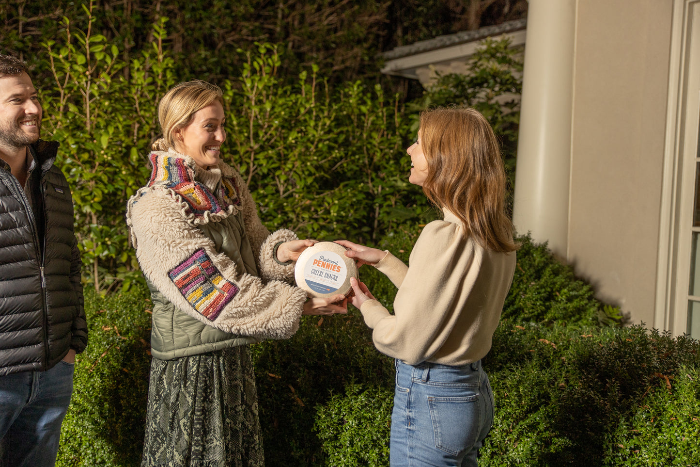 A woman gifting Piedmont Pennies cheese crackers to her friend and both smiling